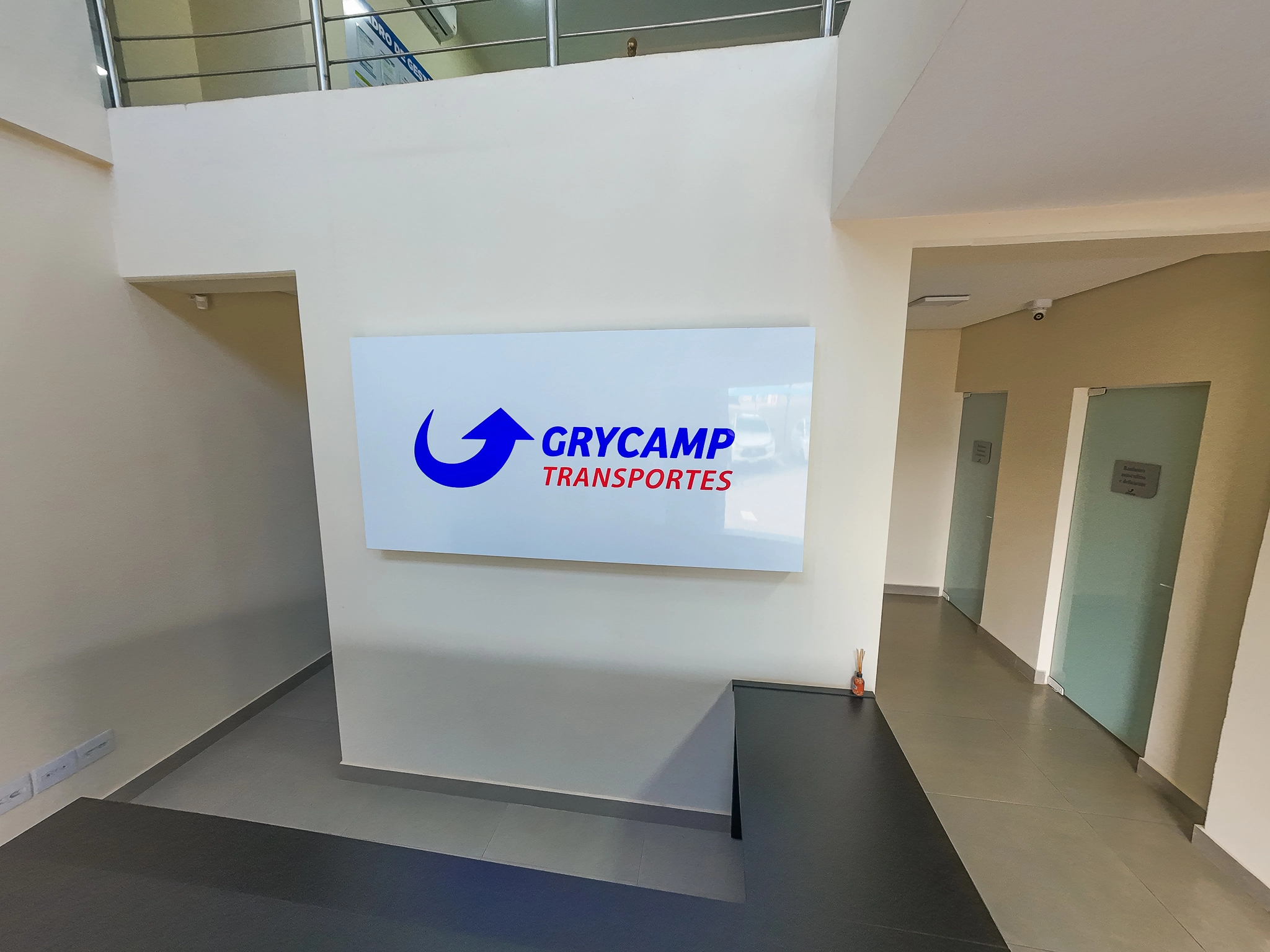 Recepção da Grycamp com painel branco exibindo o logotipo da empresa