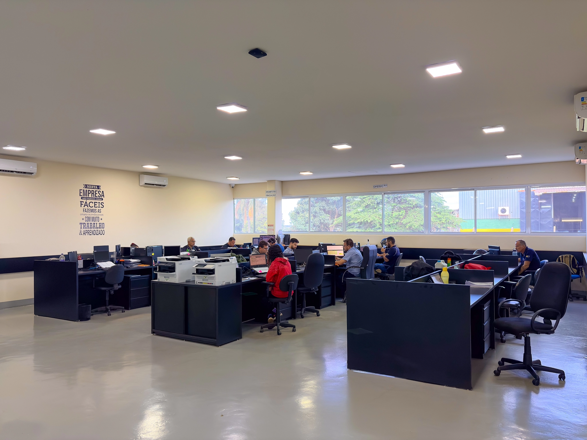 Escritório administrativo da Grycamp com colaboradores trabalhando em estações de atendimento
